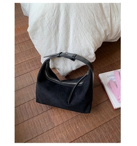 Detail of black suede half-moon tote bag with adjustable leather handle and silver zipper