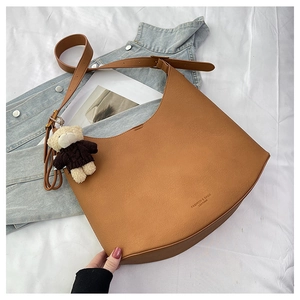 Détail du sac hobo en cuir fauve avec bandoulière réglable et breloque ourson
