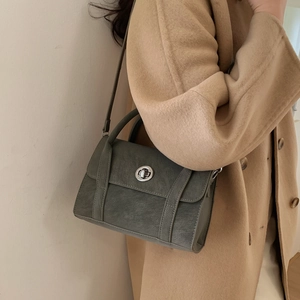 Detail of grey-green crossbody bag with silver metal twist lock and thin leather strap