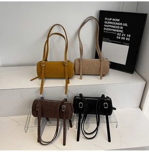Minimalist cylinder shoulder bags in four colors displayed on white marble steps