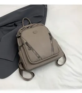 Close-up of khaki pebbled leather backpack with dual diagonal zippers and adjustable straps