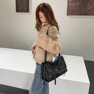 Detail of a large black messenger shoulder bag shown with an adjustable strap and flap closure