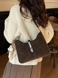 Brown suede shoulder bag with silver buckle and plush bear charm shown on model