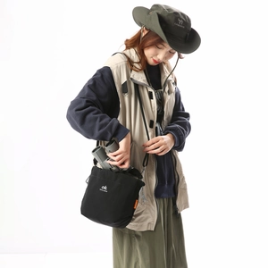 Detail of large black canvas crossbody tote bag holding binoculars for outdoor use