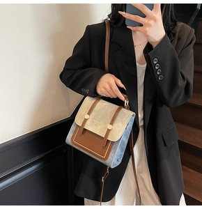 Detail of a vintage-style colorblock square handbag with gold buckles and crossbody strap