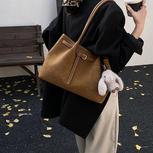 Brown faux suede tote bag with metal buckle and plush rabbit charm in autumn street style