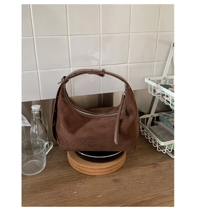 Close-up of dark brown suede hobo bag with leather handle and decorative zipper pull