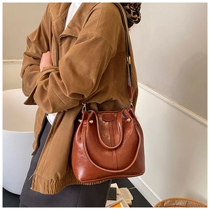 Detail der dunkelbraunen Vintage-Beuteltasche mit Kontrastnähten und breitem Webriemen