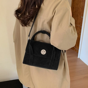 Detail of vintage black suede crossbody bag with elegant silver twist lock and slim strap