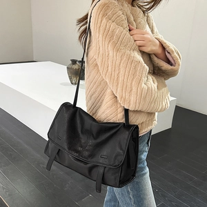 Detail shot of the side view showing the black leather messenger bag draped over a shoulder