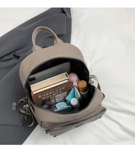 Spacious interior of khaki leather backpack holding tablet, books, and cosmetics