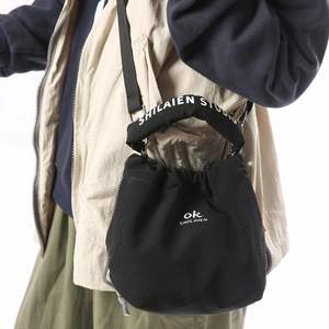 Detail of black drawstring bucket bag showing white brand logo and thick padded handle