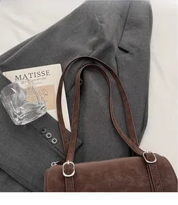 Detailed view of the brown retro cylinder shoulder bag with silver metallic buckles