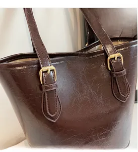 Detail of dark brown glossy leather tote featuring vintage gold buckle and hardware