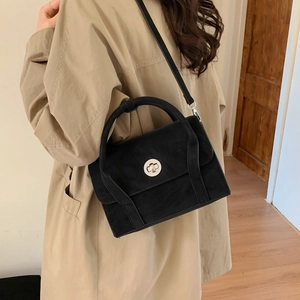 Detail view of black matte minimalist crossbody bag with metallic round twist lock closure