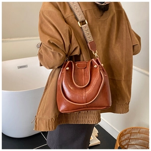 Brown vintage leather bucket bag with decorative rivets and patterned jacquard strap