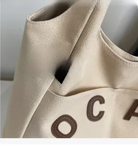 Close-up of beige canvas tote bag showing thick texture and black logo label detail