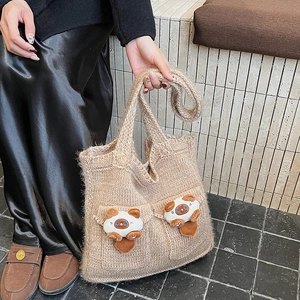 Detailed texture of camel knit shoulder bag featuring 3D plush cat charms and front pockets