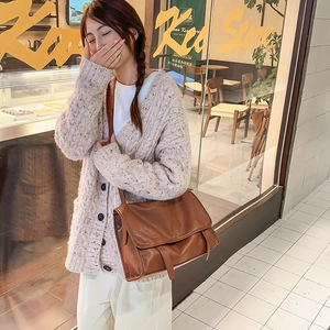 Brown vintage leather messenger bag styled with a beige chunky knit cardigan in a cafe setting