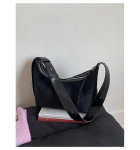 Détail du sac hobo en daim noir avec bandoulière en cuir et boucles à rivets argentés