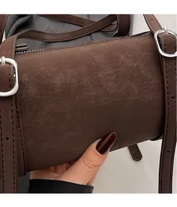 Detail of vintage brown cylinder bag with distressed texture and silver buckle
