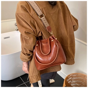 Detail of vintage brown bucket bag featuring stylish geometric pattern wide shoulder strap