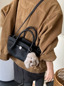 Chic black lychee grain leather bucket bag with plush dog charm and cross-body strap