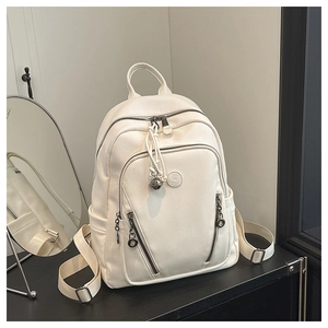 Detail of white pebbled leather backpack with metal logo and bell charm pendant