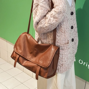 Brown vintage messenger bag with double buckles shown on model for daily commuting style