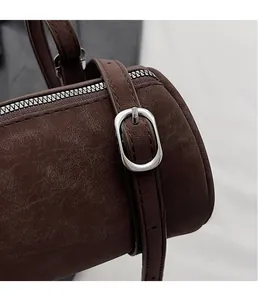 Macro detail of brown textured leather cylinder bag with shiny silver metal buckle