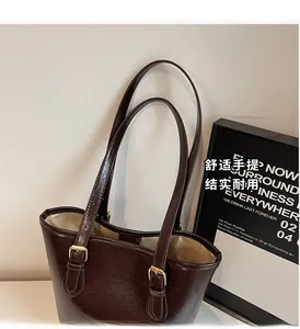 Close-up of dark brown leather tote with golden buckles and durable handle detail