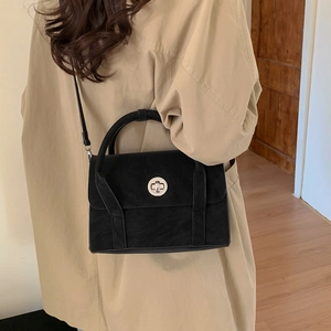 Detailed view of a black matte crossbody bag with silver round lock worn by a model