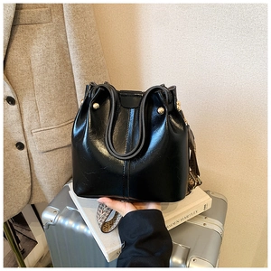 Detail of black bucket bag with gold rivets and ethnic style woven shoulder strap
