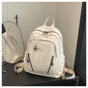 Detail view of white lychee texture backpack with metallic charms on a creative display