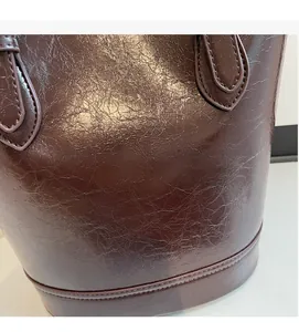 Detail of premium textured brown leather bucket bag with reinforced stitching on handle