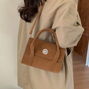 Detail of a vintage brown crossbody bag with matte texture and silver turn-lock closure