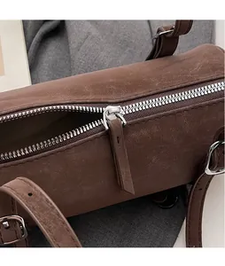 Macro shot of silver metal zipper and extended brown leather puller on a barrel bag