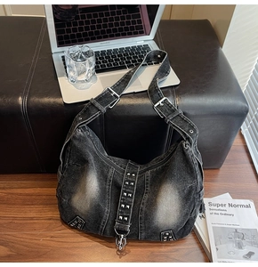 Detailed macro view of vintage washed denim shoulder bag featuring silver metal rivets