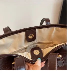 Detail of the dark brown tote bag interior featuring magnetic closure and inner zip pocket