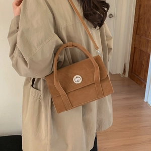 Detail of vintage brown suede crossbody bag with silver round metal clasp and top handle