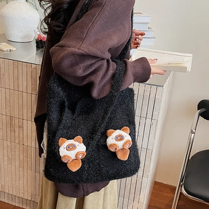 Detail of black textured tote bag featuring cute plush cat patches in a cozy setting