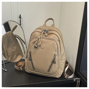 Close-up of beige lychee grain leather backpack with silver zippers and metallic logo detail