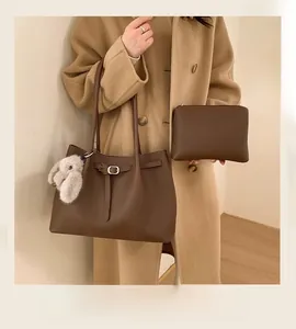 Detailed close-up of brown leather tote bag with inner pouch and white rabbit charm accessory