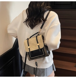Detail of a retro two-tone mini backpack with metallic handle on model in indoor setting