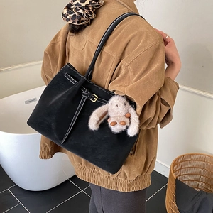 Close-up of large black tote bag with white stitching and a cute plush bunny charm