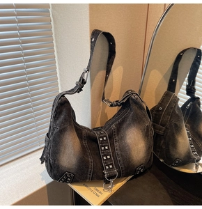 Detail view of washed denim hobo bag featuring silver rivets and wide adjustable strap