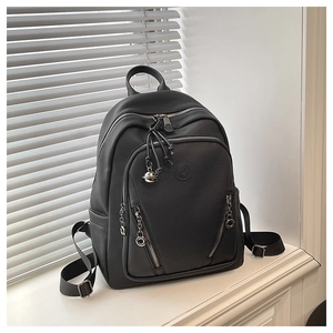 Detail of black pebbled leather backpack showing multi-zipper pockets and brand emblem
