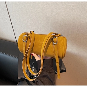 Detail view of mustard yellow cylinder bag featuring retro leather texture and dual straps
