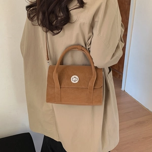 Detailed view of a brown vintage crossbody bag styled with a beige trench coat
