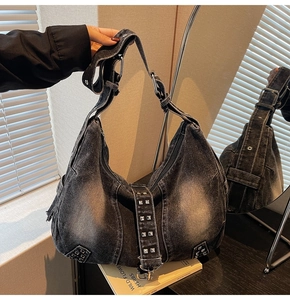 Detailed macro view of dark grey washed denim hobo bag with silver square rivets and wide strap
